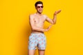 Photo of pretty adorable young man naked torso wear dark eyewear dancing smiling isolated yellow color background Royalty Free Stock Photo