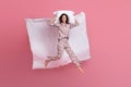 Photo of pretty adorable young woman dotted sleepwear jumping high lying pillow blanket isolated pink color background