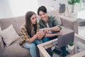 Photo of pretty attractive young lovers dressed casual clothes sitting sofa reading modern device smiling indoors Royalty Free Stock Photo