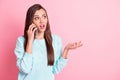 Photo of pretty brown haired annoyed young woman talk phone look copyspace chatting isolated on pastel pink color