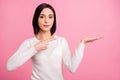 Photo of pretty business lady indicating finger on open palm presenting new product wear white pullover isolated pink