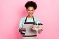 Photo of pretty cheerful cashier girl hold barista coffee ask payment wear apron striped shirt isolated pink color Royalty Free Stock Photo