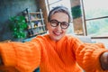 Photo of pretty cheerful elderly lady wear orange pullover spectacles recording video vlog indoors apartment room Royalty Free Stock Photo