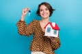 Photo of pretty cheerful girl toothy smile hands hold showing little house key isolated on blue color background Royalty Free Stock Photo