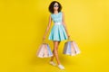 Photo of pretty confident dark skin girl dressed blue clothes eyewear smiling walking holding bargains isolated yellow Royalty Free Stock Photo