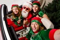 Photo of pretty cute santa claus assistants driving car showing v-sign thumbs up  white color background Royalty Free Stock Photo