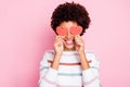 Photo of pretty dark curly skin lady holding in hands little red paper hearts hiding flirty eyes wear white striped Royalty Free Stock Photo