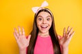 Photo of pretty excited small schoolgirl dressed pink t-shirt smiling rising arms isolated yellow color background