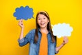 Photo of pretty excited student girl wear denim shirt smiling holding two mind clouds yellow color background