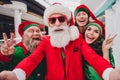 Photo of pretty funny santa claus assistants wear costumes showing c-signs tacking self photo indoors shopping center