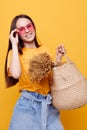 photo pretty girl Beach bag fashion in yellow t-shirt denim shorts yellow background Royalty Free Stock Photo