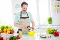 Photo of pretty good mood age man dressed blue t-shirt apron smiling cooking frying eggs smiling indoors home room Royalty Free Stock Photo