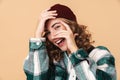 Photo of pretty joyful woman in knit hat laughing and covering her face
