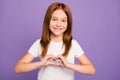 Photo of pretty little ginger lady making heart figure with fingers symbolizing children cardiology safety wear white t