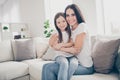 Photo of pretty little girl young charming mommy hugging holding each other close affectionate sitting comfy sofa spend