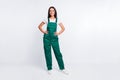 Photo of pretty positive lady hands hips look camera wear green overall isolated white color background Royalty Free Stock Photo