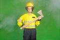 Photo of pretty serious young firewoman dressed yellow uniform helmet holding hatchet isolated green color background