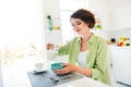 Photo of pretty shiny girl wear green shirt preparing morning cereal pouring milk indoors kitchen room Royalty Free Stock Photo