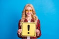 Photo of pretty shiny young lady wear plaid shirt holding exclamation point board isolated blue color background Royalty Free Stock Photo