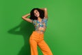 Photo of pretty young chevelure hair woman vintage top combinated with orange jeans relaxed touch hair isolated on green