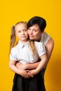 Photo of pretty young mommy hold arms hugging little daughter good mood, yellow color background