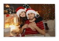 Photo printed on canvas. Happy young couple in Santa hats celebrating Christmas at home Royalty Free Stock Photo