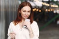 Photo of prosperous female business worker has break after work, sends text messages, holds cell phone in hand, dressed in white