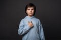 Photo of puzzled boy 10-12 years old pointing finger at herself. Studio shot, gray background. Facial expression concept Royalty Free Stock Photo