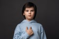 Photo of puzzled boy 10-12 years old pointing finger at herself. Studio shot, gray background. Facial expression concept Royalty Free Stock Photo