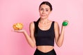 Photo of questioned unsure young woman dressed sportive outfit holding potato crisps dumbbell isolated pink color Royalty Free Stock Photo