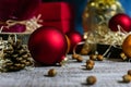 Photo of red balls for decorating a Christmas tree on a wooden table in defocus among cones and hazelnuts