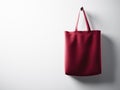 Photo red cotton textile bag hanging right side. Empty white wall background. Highly detailed texture, space for advertising. Hori