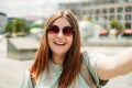 Photo relaxed charming positive young woman hold camera and make selfie summer outside in city center outdoors