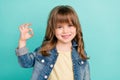 Photo of reliable little girl show okey sign approve choice wear jeans jacket aquamarine color background