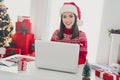 Photo of remote programmer lady sit table typing netbook email wear santa hat pullover in decorated x-mas home indoors