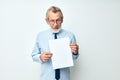 Photo of retired old man holding documents with a sheet of paper light background Royalty Free Stock Photo