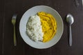 A photo rice with fried egg omelet, with spoon and fork on white plate. isolated on wood background. breakfast with omelet in. Royalty Free Stock Photo