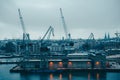 Photo of river, floating cranes, buildings on river bank