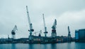 Photo of river, floating cranes, buildings on river bank