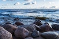 Photo of the rocks on the beach of the finnish bay in St. Petersburg. Choppy sea and a cloudy sky on the background