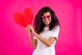 Photo of romantic curly millennial lady hold heart look empty space wear white t-shirt isolated on pink color background