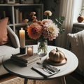 Photo of a round wooden table in Scandinavian style, seen from above. On it, there's a bouquet of dahlias, a candle