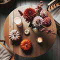 Photo of a round wooden table in Scandinavian style, seen from above. On it, there's a bouquet of dahlias, a candle