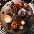 Photo of a round wooden table in Scandinavian style, seen from above. On it, there's a bouquet of dahlias, a candle