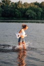 Photo of a running blonde in profile. A young woman in a white top and shirt and denim shorts runs freedom on the water