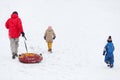 Photo of running father with tubing, son and daughter on winter park Royalty Free Stock Photo