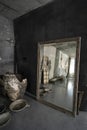 Photo of rustic concrete designer interior with old wooden door, bench, big mirror, artistic vase and bowls. Natural sunlight