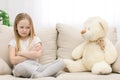 Photo of sad blond girl looking at teddy bear. Royalty Free Stock Photo