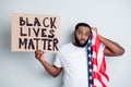 Photo of sad hurted dark skin american guy protester hold placard usa flag touch head police voilence stand against afro