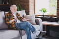 Photo of sad lonely retired man dressed plaid shirt watching movie sitting couch holding nursery cane indoors apartment